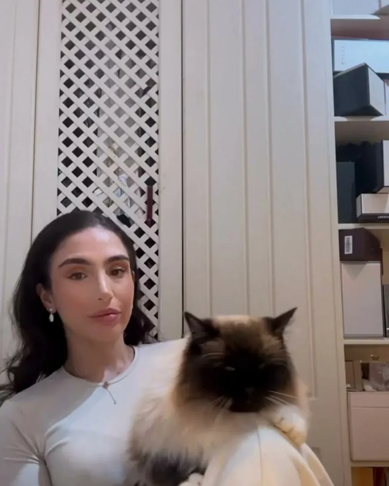 Lala at her vanity applying makeup, her ragdoll cat Kiara resting on her lap