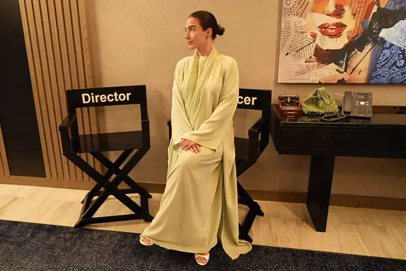 Amaya Lala seated in a sage abaya between director and producer chairs