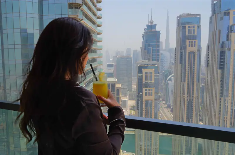 Amaya Lala looking out over the city from a high balcony, morning