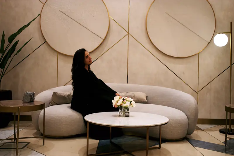 Amaya Lala seated in a hotel lounge, brass detailing behind her